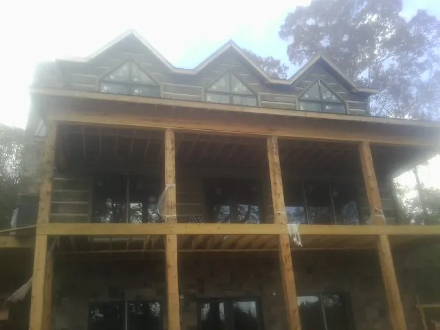 Dormers and porch framing on a large log home under construction — Roof Coating work by our crew in Manning