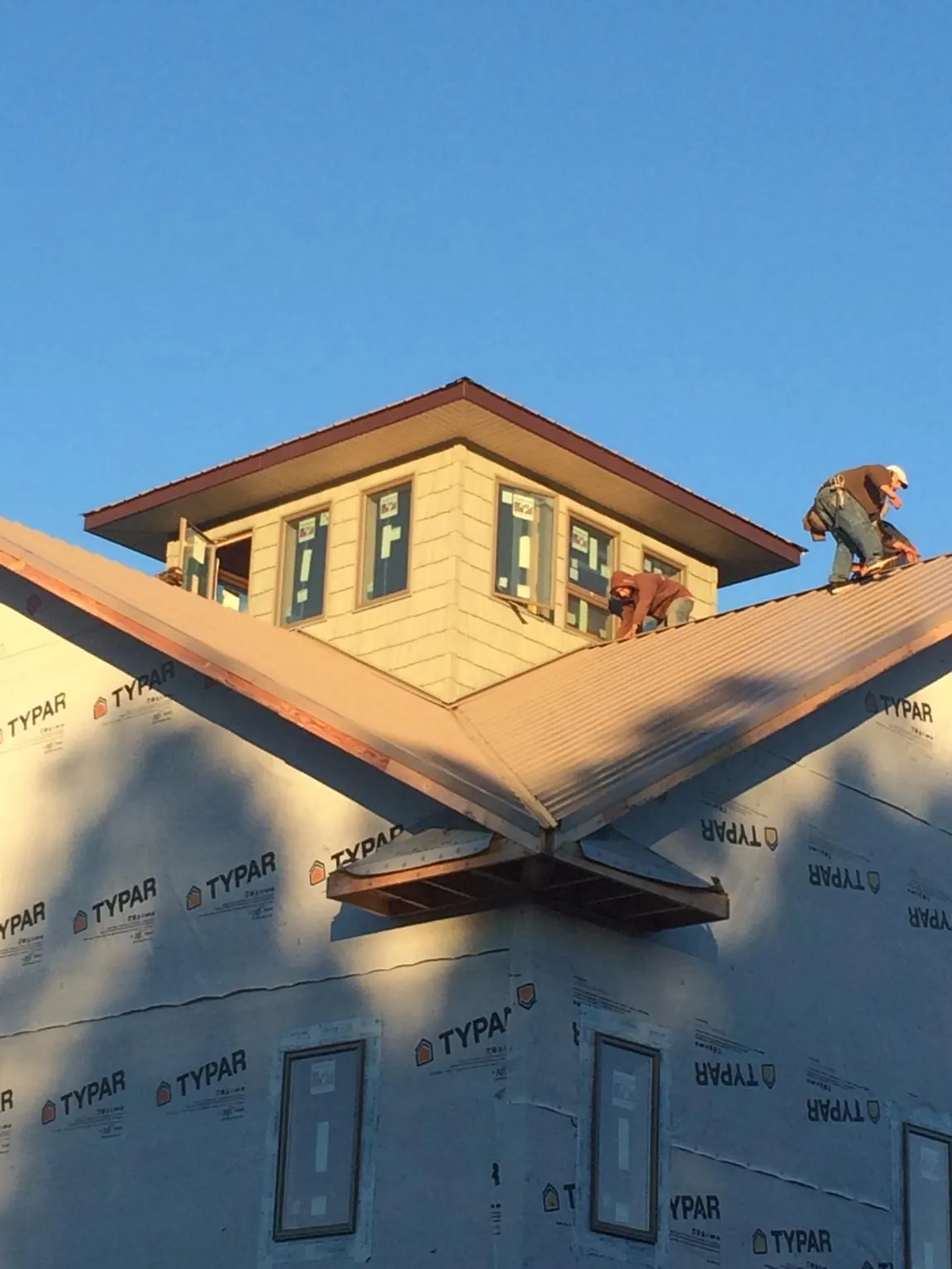 Roofers working around a rooftop cupola on a new metal roof at sunset — Roof Waterproofing in Manning by Roofing Brothers